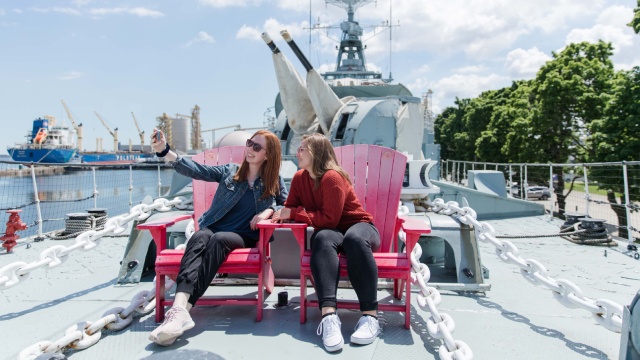 Deux jeunes femmes sur les chaises rouges de Parcs Canada sur le pont du destroyer NCSM Haida.